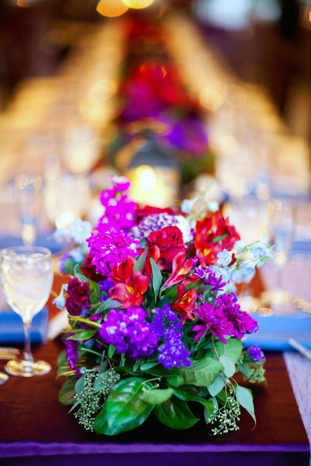 Long table centerpieces with jewel tone flowers and candles