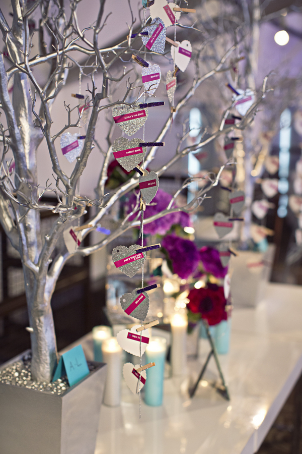 silver glitter heart escort cards hanging on silver potted tree with purple glitter clothespins