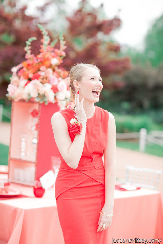 Red dress bridesmaid with flower bracelet and flower ring smiling