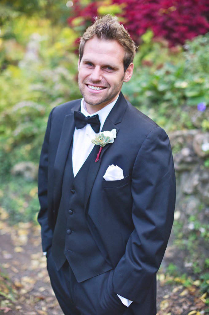 Groom in black tux and bowtie with succulent boutonniere