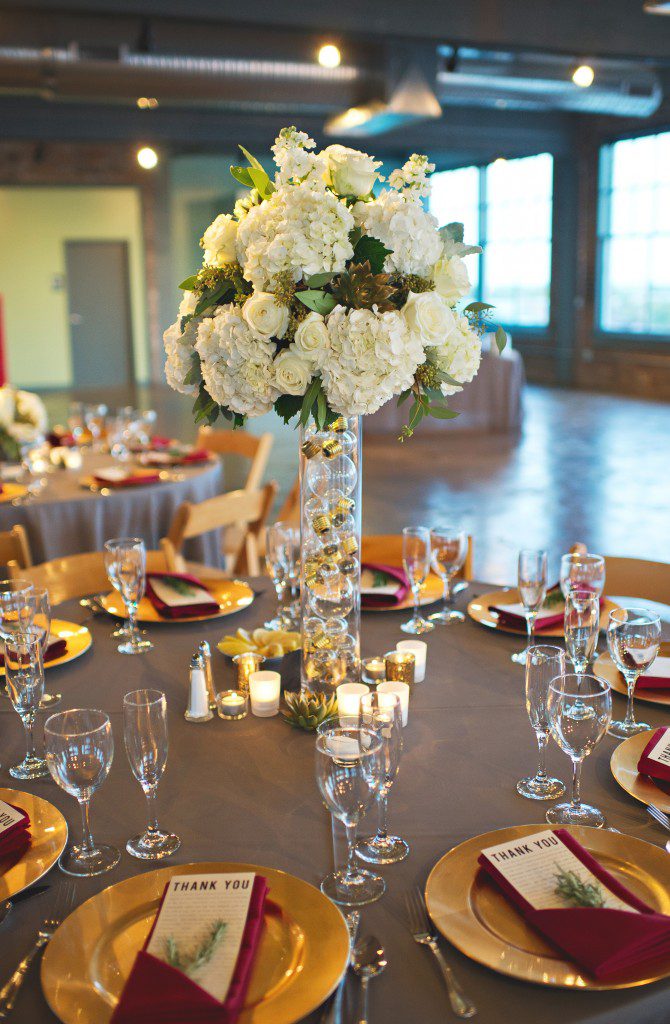 Tall white hydrangea and rose centerpieces on vase filled with lightbulbs