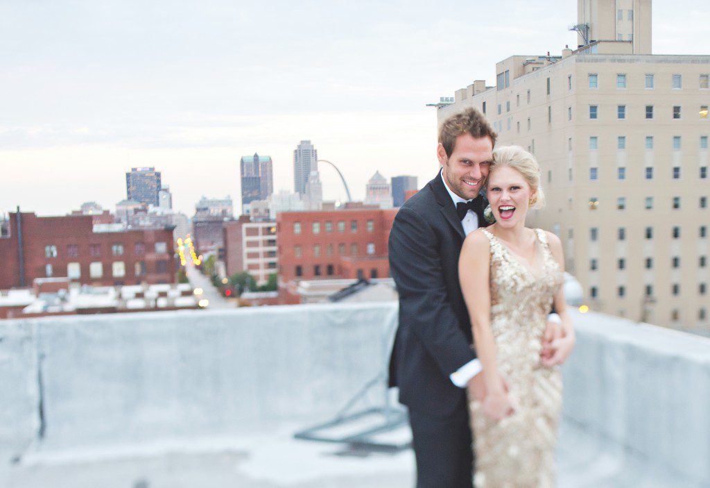 Bride and groom on rooftop with St Louis Arch in background