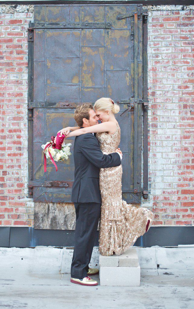 Groom and bride in gold sequin wedding dress in front of vintage metal door
